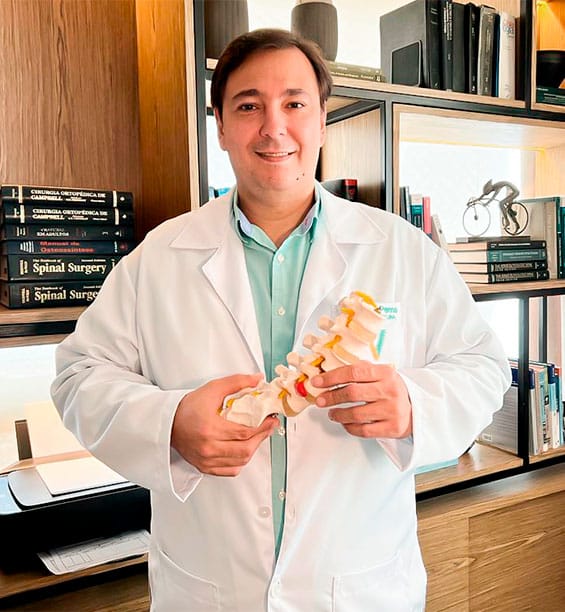 Dr. Marcio ortopedista Penna de Carvalho, médico cirurgião de coluna, segurando uma maquete de coluna vertebral
