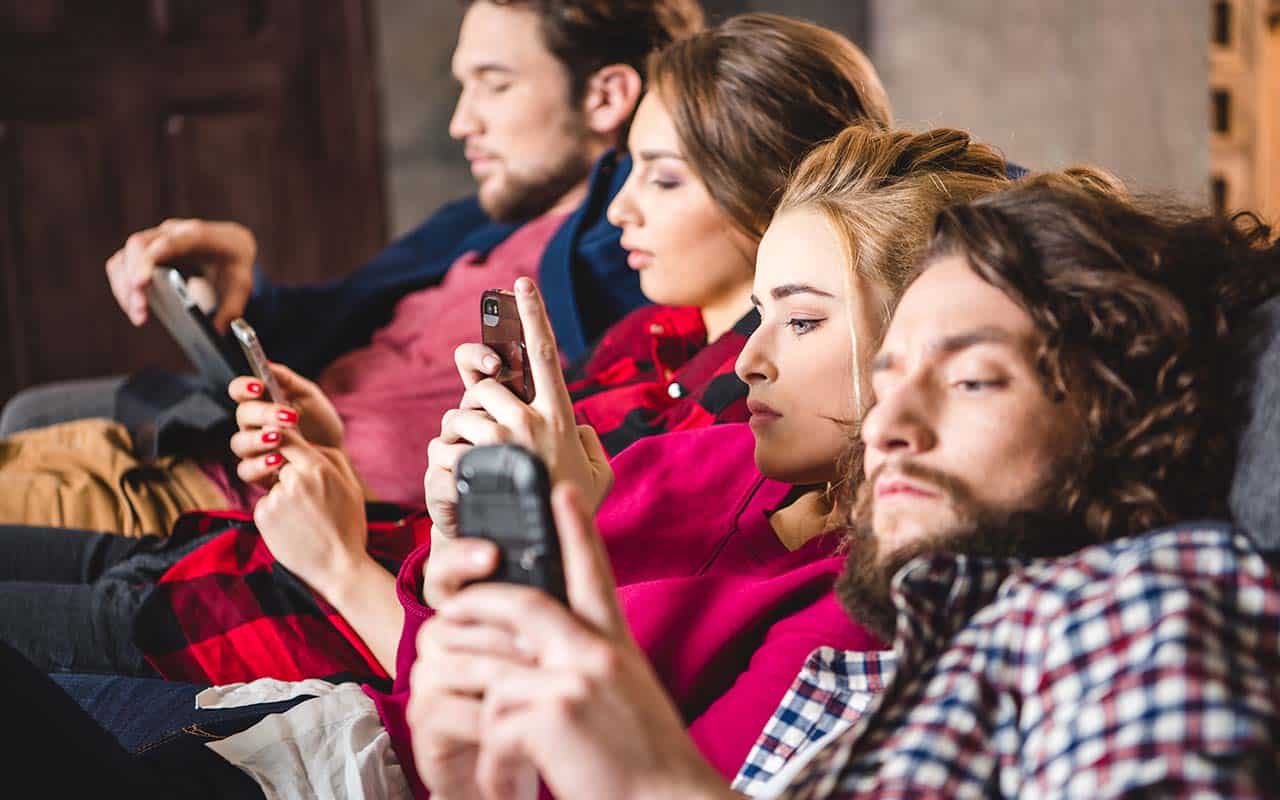 Jovens sentados com má postura olhando o celular - site Dr. Marcio Penna ortopedista especialista em coluna