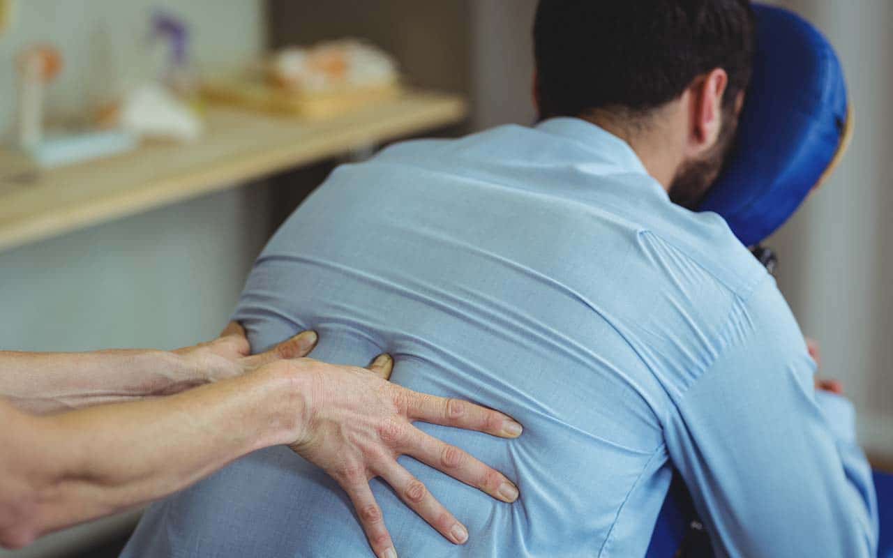 Mulher fazendo massagem em homem com problemas de coluna - site Dr. Marcio Penna ortopedista especialista em coluna