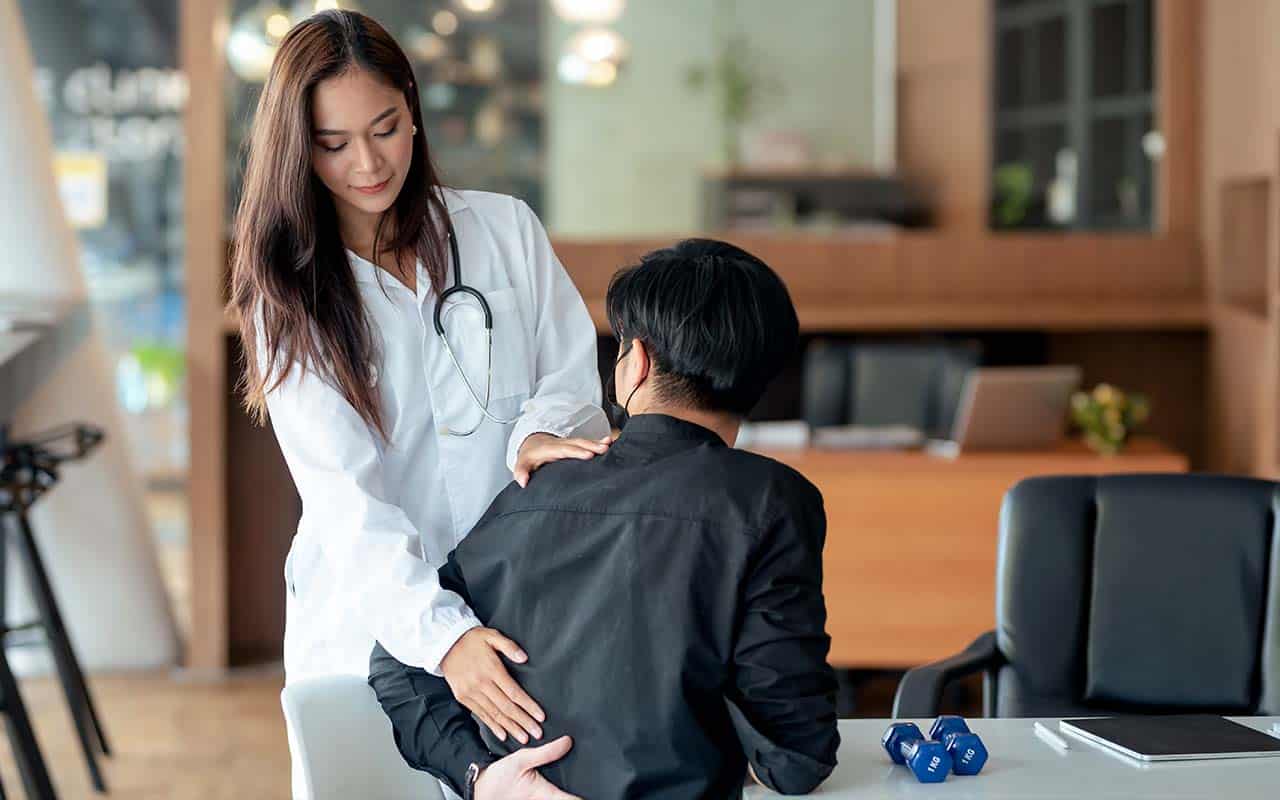 doutora ortopedista examinando a parte baixa das costas deum paciente - site Dr. Marcio Penna ortopedista especialista em coluna